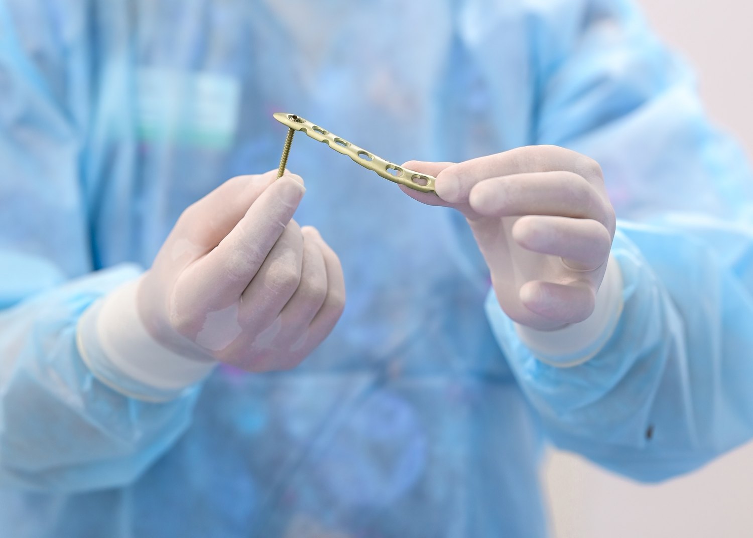 Surgeon holding an upper extremity orthopedic plate and screw